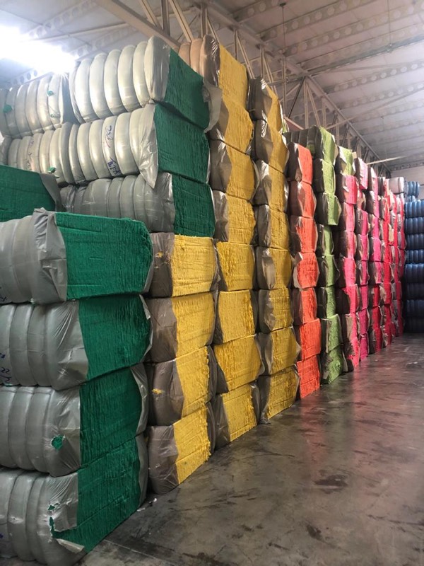 Warehouse rows of green, yellow and orange textile bales